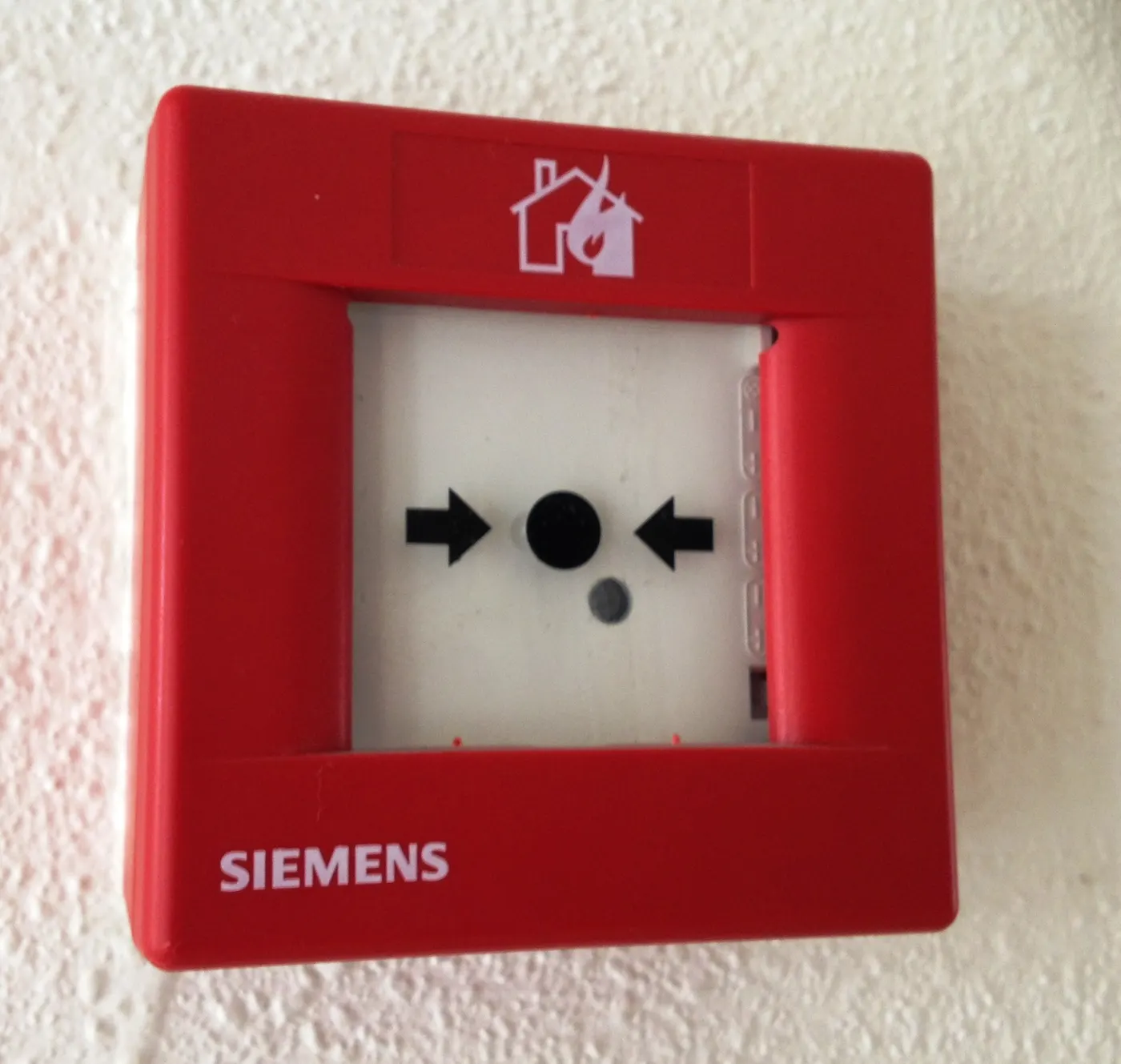 Red manual call point (fire alarm push button) on a wall